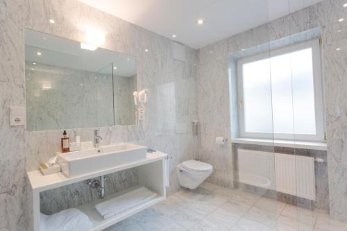 a bathroom with a tub and a sink and a toilet at Boutique & Gourmet Hotel Orso Grigio in San Candido