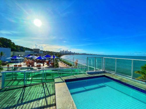 a swimming pool on top of a building next to the water at Flat Studio Beira Mar Cabo Branco in João Pessoa