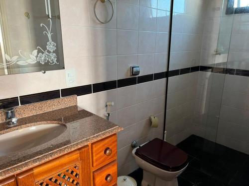 a bathroom with a sink and a toilet and a mirror at Ubatuba - Frente Mar Praia Grande in Ubatuba
