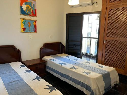 two beds sitting in a room with a window at Ubatuba - Frente Mar Praia Grande in Ubatuba
