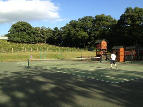 two people playing tennis on a tennis court at Carden Park Hotel, Golf Resort and Spa in Tilston