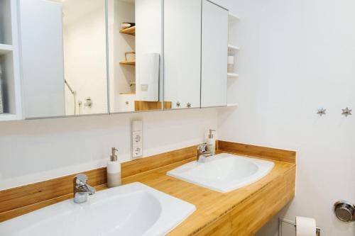 2 lavabos en un baño con armarios blancos en Norderhoog-Whg-35-1-OG-Wohnung-35, en Westerland