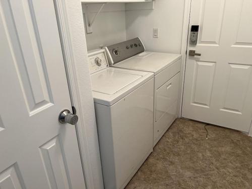een kleine witte wasruimte met een wasmachine en droger bij 3 Bedroom 2 Bath Oasis in Cozy Neighborhood in Las Vegas