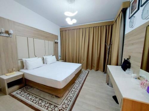 a bedroom with a large white bed and two tables at 1BR Warm and comfortable APT in Sharjah