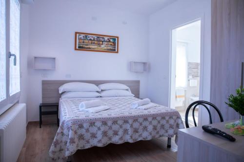 a white bedroom with a bed with a table at Affittacamere Ceccarini in Riccione
