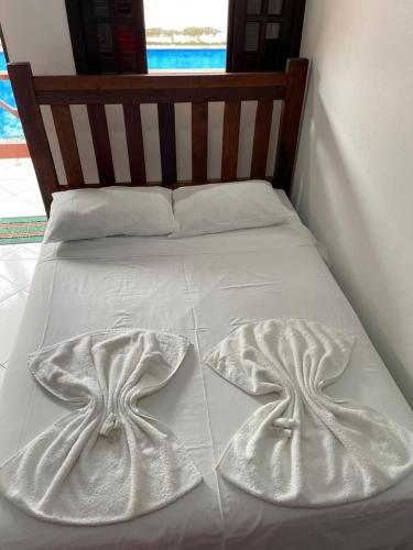 a bed with white sheets and two towels on it at Pousada Canto Juquehy in Juquei