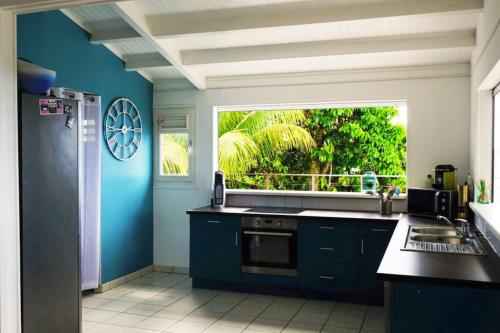 une cuisine aux murs bleus et une grande fenêtre dans l'établissement INCROYABLE Villa avec vue mer et piscine privative au sel, à Sainte-Luce