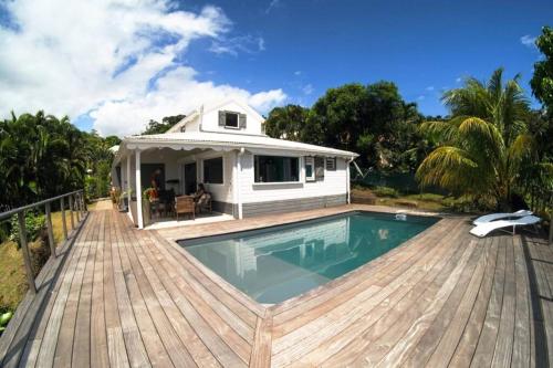 une maison avec une piscine sur une terrasse en bois dans l'établissement INCROYABLE Villa avec vue mer et piscine privative au sel, à Sainte-Luce