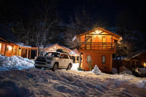 un coche aparcado frente a una casa en la nieve en Cabañas Tronco Mayen, en Las Trancas