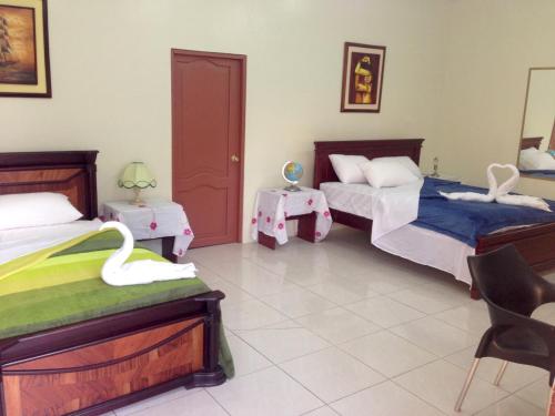 a bedroom with two beds and two tables with swans on them at Hotel MundialCity in Guayaquil