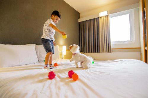 a young boy playing with a dog on a bed at ibis Criciuma in Criciúma