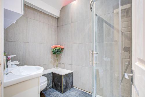 a bathroom with a shower and a toilet and a vase of flowers at Beautiful One Bedroom Apartment in Brentwood
