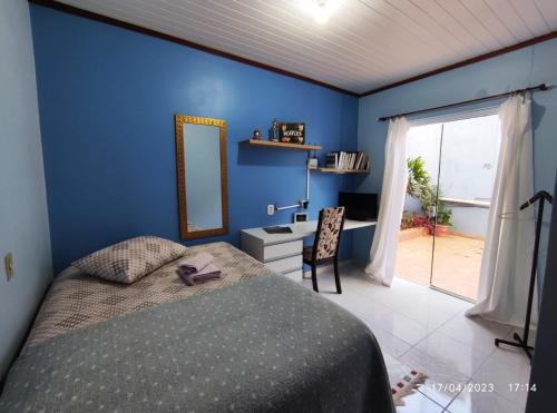 a bedroom with blue walls and a bed and a mirror at Quarto, piscina e acesso exclusivo in Encantado