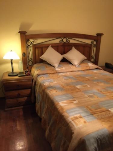 a bedroom with a large bed with a lamp on a night stand at El Seminario Hospedaje in Cajamarca