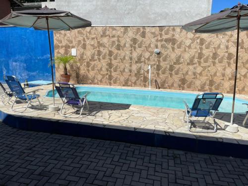 three chairs and umbrellas next to a swimming pool at Pousada Canto Juquehy in Juquei