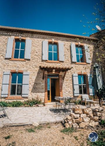 - un bâtiment en pierre avec une table et des chaises devant dans l'établissement Maison de village avec piscine, à Orsan