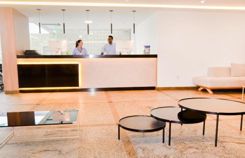 two people standing in a lobby with two tables at El Aram Beach Boa Viagem in Recife