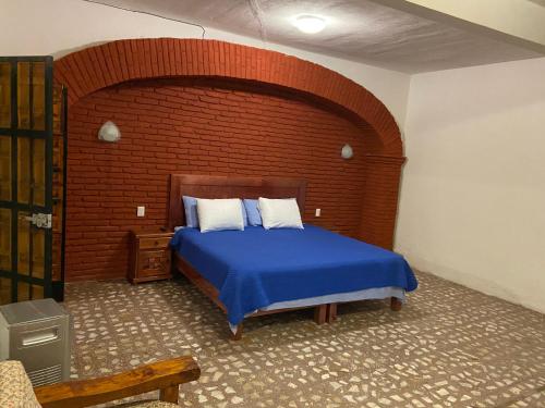 a bedroom with a blue bed with a brick wall at EL GRAN TORIL in Taxco de Alarcón