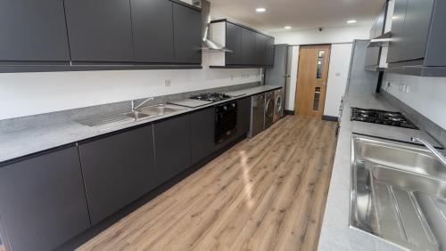 cocina con electrodomésticos de acero inoxidable y suelo de madera en FREE PARKING Cosy Studios close to city and QE and UOB! en Birmingham