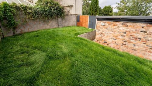een tuin met groen gras naast een stenen muur bij FREE PARKING Cosy Studios close to city and QE and UOB! in Birmingham