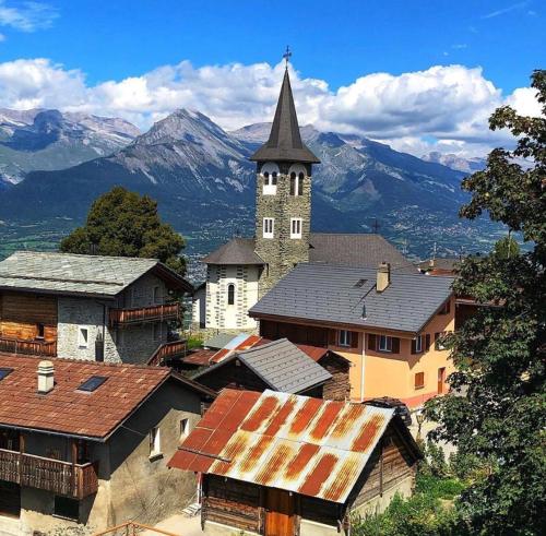 a village with a church and mountains in the background at Chalet Alpin suisse in Veysonnaz