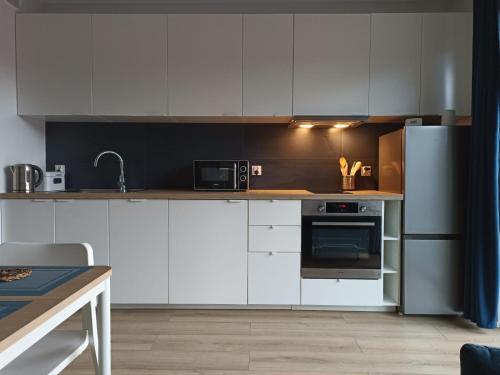 a kitchen with white cabinets and a stainless steel refrigerator at Apartament Alicja in Międzywodzie
