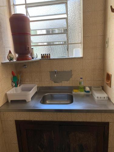 a kitchen counter with a sink and a mirror at Quarto COMPÔ 6 in São João del Rei