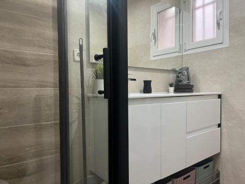 baño con lavabo y puerta de ducha acristalada en Luminoso apartamento con precioso y amplio patio, en Carabanchel Alto