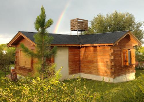 a wooden cabin with a rainbow in the background at Cabaña en Villa Amancay in Villa Amancay