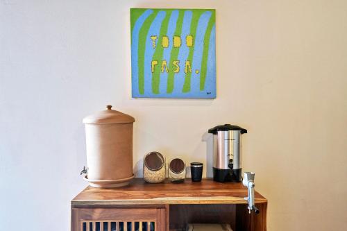 a table with a coffee maker and a painting on the wall at Casa Calocita in Santa Teresa Beach
