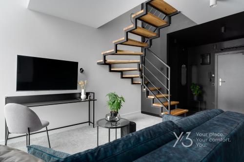 a living room with a blue couch and a spiral staircase at Saint Martin Residence Old Town with Wellness in Poznań