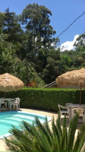 einen Pool mit Stühlen und Sonnenschirmen in der Unterkunft Pousada Valle das Aguas in Maria da Fé