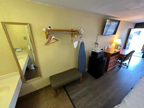 Habitación con espejo, silla y escritorio. en Days Inn & Suites by Wyndham Pigeon Forge, en Pigeon Forge