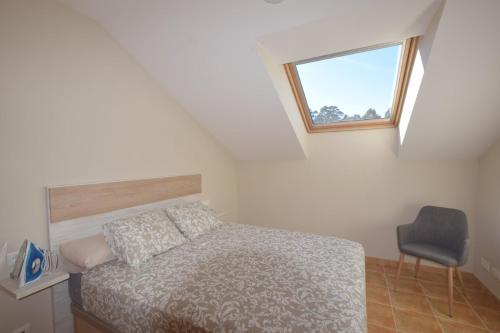 a bedroom with a bed and a window and a chair at Apartamento Playa de Quenxe in Corcubión