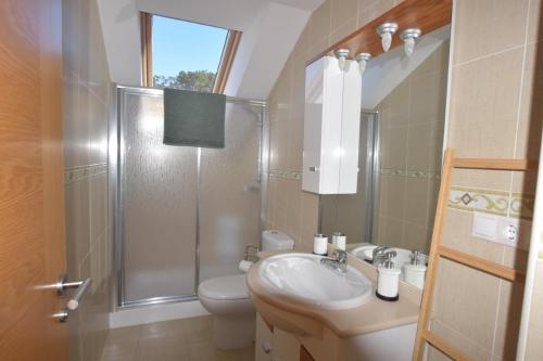 een badkamer met een douche, een wastafel en een toilet bij Apartamento Playa de Quenxe in Corcubión