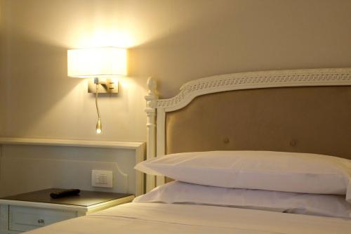 a bedroom with a bed with a lamp on the wall at Parco dei Principi Boutique Hotel in Rimini