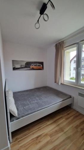 um quarto com uma cama e uma janela em Apartament CALMA em Krynica Morska