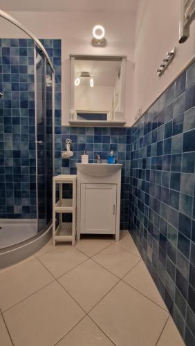 a bathroom with blue tiles and a sink and a shower at Apartament CALMA in Krynica Morska