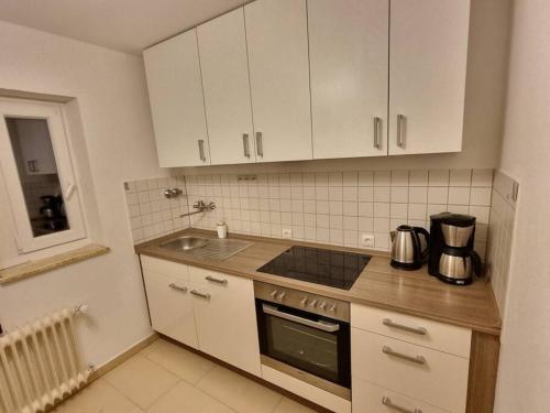eine Küche mit weißen Schränken, einem Herd und einer Spüle in der Unterkunft Viktoria's Wohnung in Kaarst in Kaarst