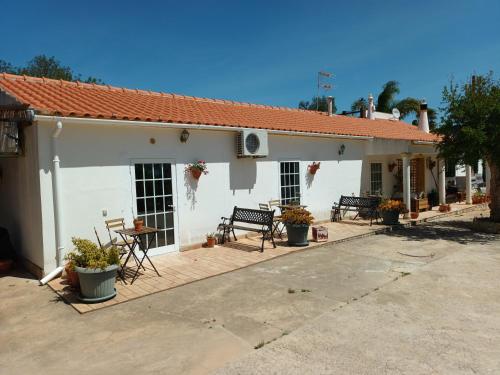 a white building with chairs and a table at B&B Quinta da Romãzeira in São Bartolomeu de Messines