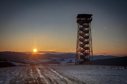 a tower on top of a snow covered hill with the sunset at Bogdanówka in Skalnik