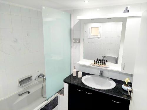 uma casa de banho com um lavatório, um espelho e uma banheira em ZETA'S HOUSE em Alikanás
