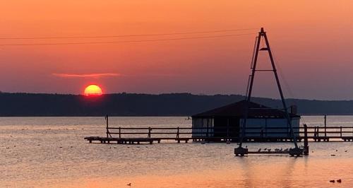 a dock in the water with a sunset in the background at Przy Złotych Piaskach 1 in Sława