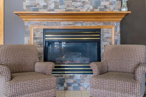 two chairs sitting in front of a fireplace at AmericInn by Wyndham Cedar Rapids North in Cedar Rapids