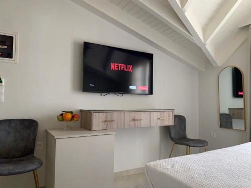 a tv on a wall in a bedroom with two chairs at Rouchotas Apartments in Argostoli