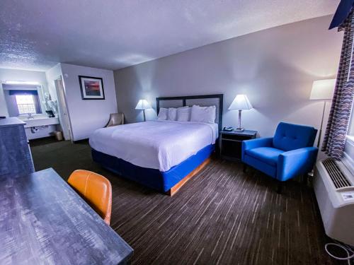 Pokój hotelowy z łóżkiem i niebieskim krzesłem w obiekcie Salt Creek Lodge w mieście Graham