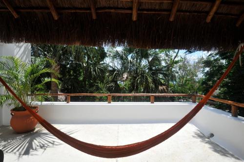 a hammock hanging from a thatch roof on a porch at Hotel Rancho Encantado in Bacalar
