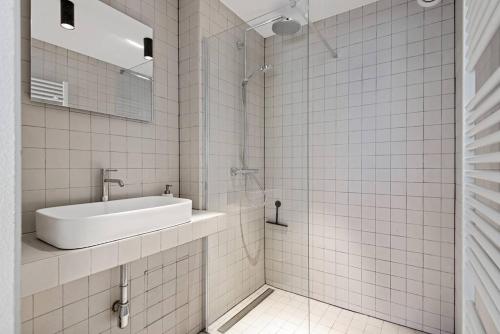 a white tiled bathroom with a sink and a mirror at Ramón Studio in Antwerp