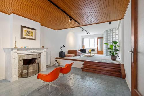 a living room with a fireplace and orange chairs at Ramón Studio in Antwerp