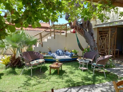 un patio trasero con un árbol, sillas y una mesa en Casa Éolica en Barra Grande